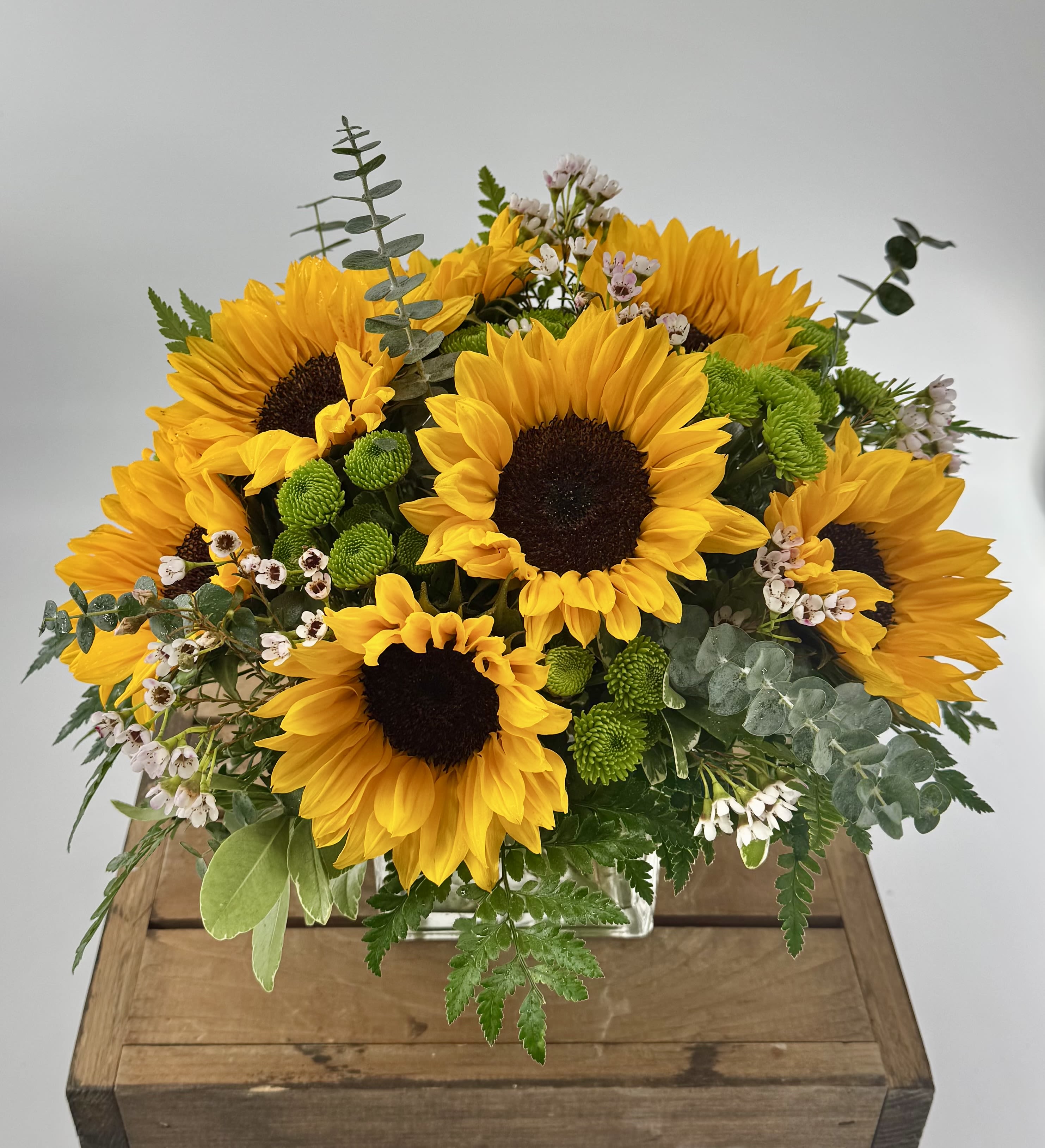 Sunflower bouquet with green accents in a low rectangular container