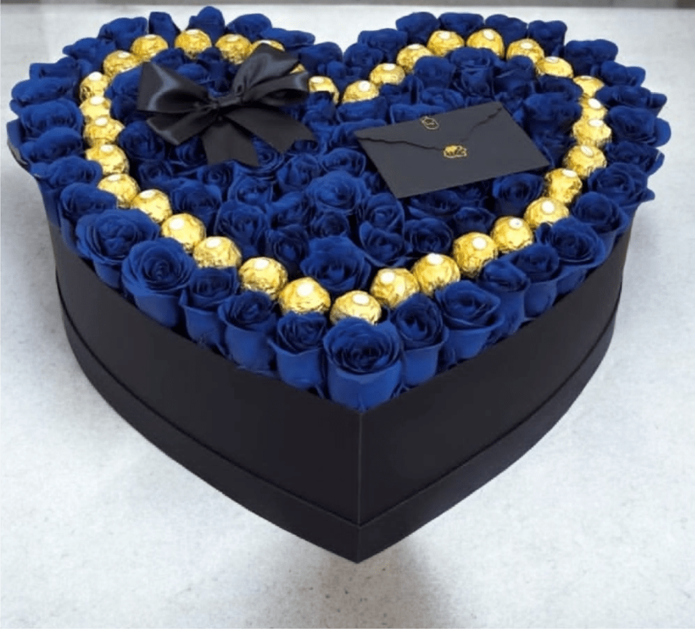Juan - A dramatic heart-box and bouquet collection built to make someone feel truly adored: Juan combines densely packed roses in rich reds, soft lavenders, pinks, whites and royal blues into romantic anniversary bouquets and love-and-romance gifts. Whether you choose the bold red dome wrapped in printed coordinating paper or the luxe heart-shaped black box of deep blue roses rimmed with gold-wrapped chocolates, the presentation reads like a declaration-perfect for anniversaries, Valentine's Day, birthdays, or a just-because romantic surprise.  Each style features tightly clustered, full rose heads for a lush, velvety texture and polished finish. Options include a rounded hand-tied bouquet wrapped in layered pale or lavender papers with a pink ribbon and mesh wrap; a striking red bouquet in patterned red paper with a black ribbon bow; or an upscale black heart box filled with royal/deep blue roses, a border of gold-wrapped chocolates, a black envelope, brand card, and decorative accents. Sizes are presentation-ready and arrive gift-wrapped for immediate giving.  This is an ideal gift set for saying "thank you," celebrating spring moments, or marking a special birthday with romance and flair - the person you're thinking of will feel seen and celebrated. For best care, keep roses in a cool spot away from direct sunlight; if moved to a vase, refresh the water to extend bloom life.