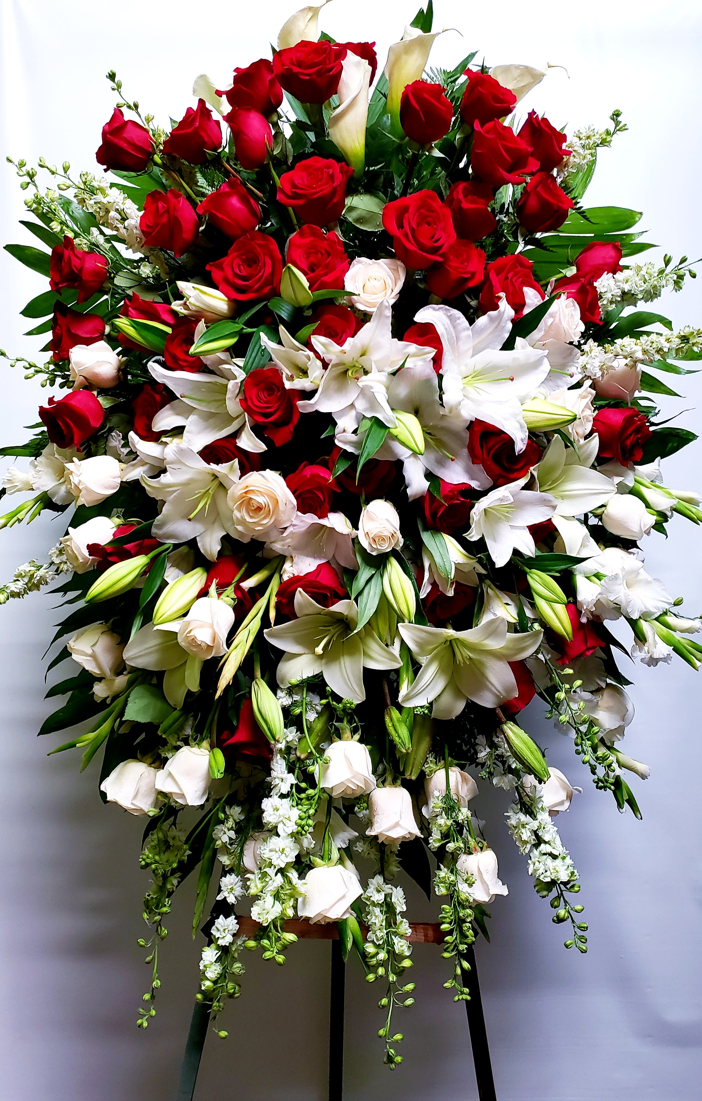 Large standing spray of red roses and white lilies with trailing white flowers