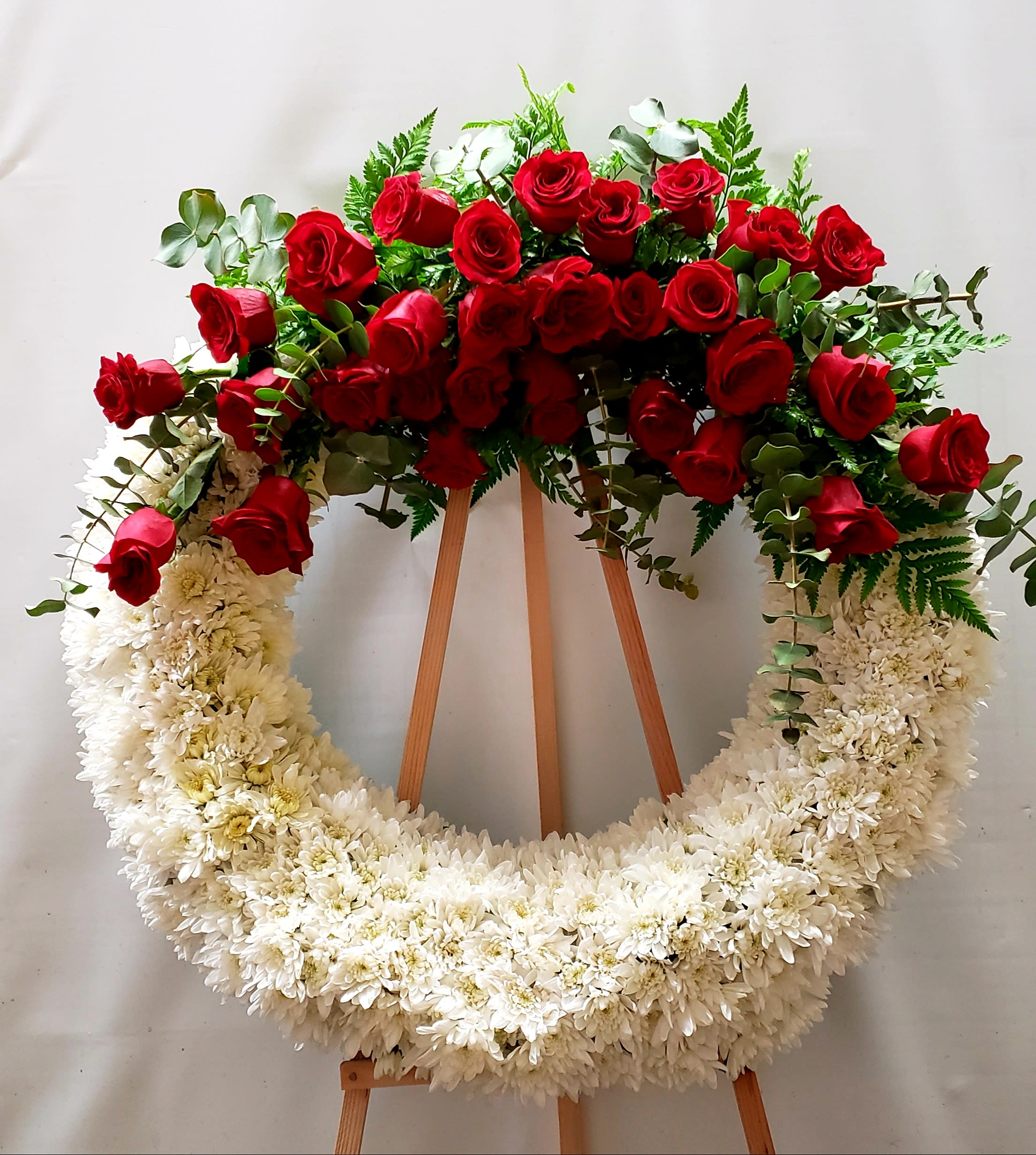 Red roses and white chrysanthemum wreath on a wooden easel