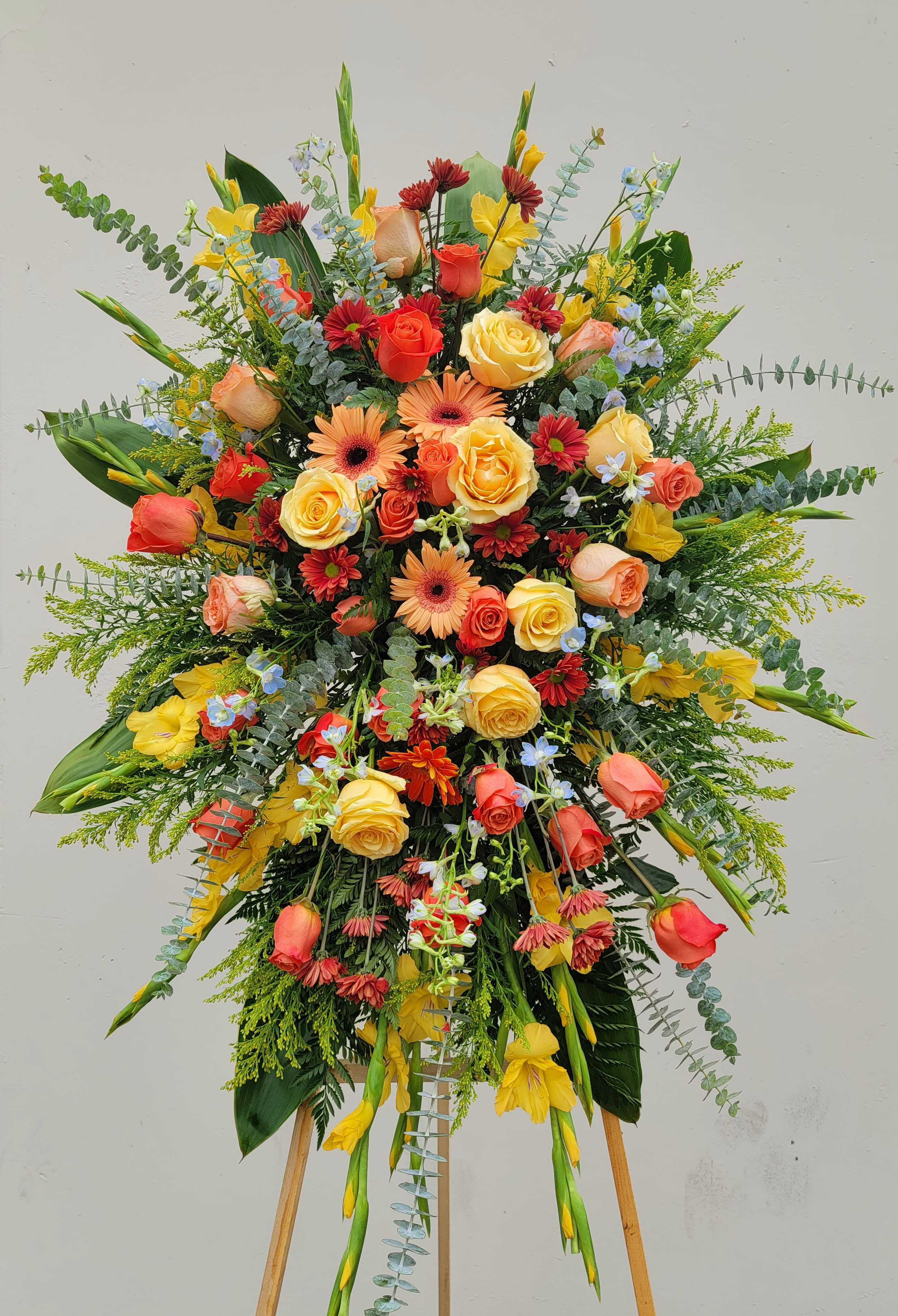 Large standing floral spray with roses, gerbera daisies, and yellow blooms