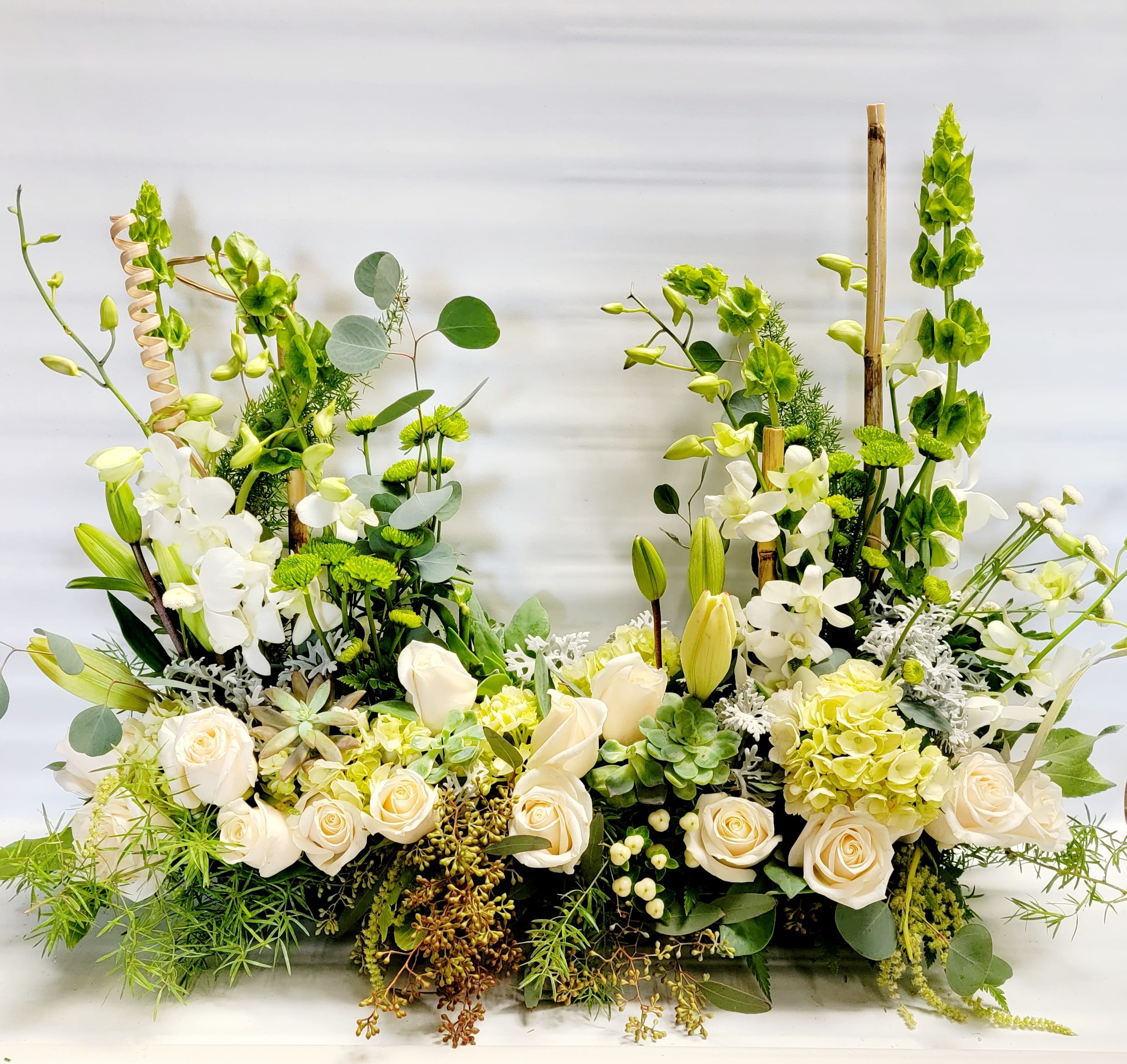 Large white and green floral arrangement with roses, lilies, and orchids