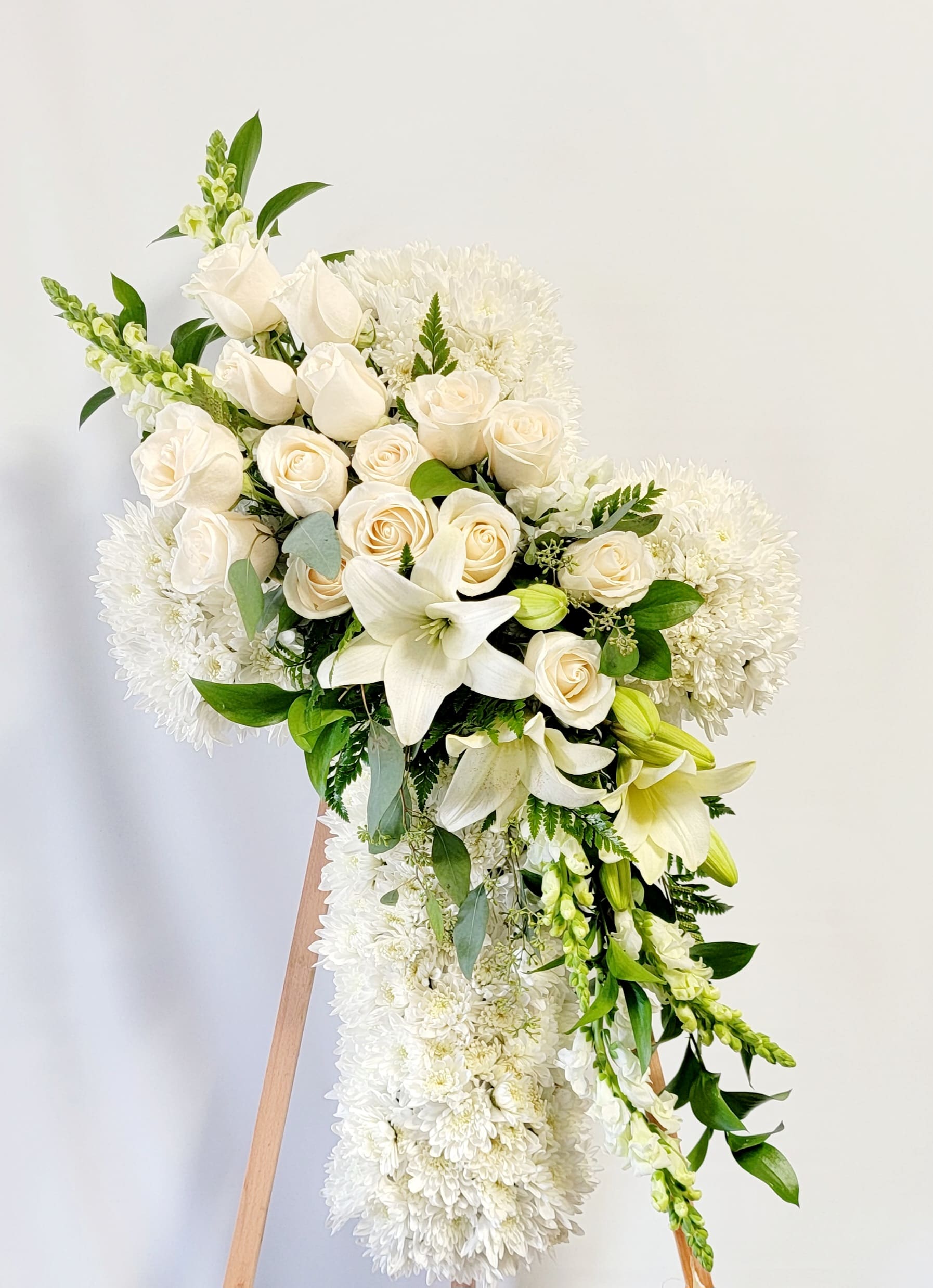 White floral standing spray with roses, lilies, and chrysanthemums on an easel