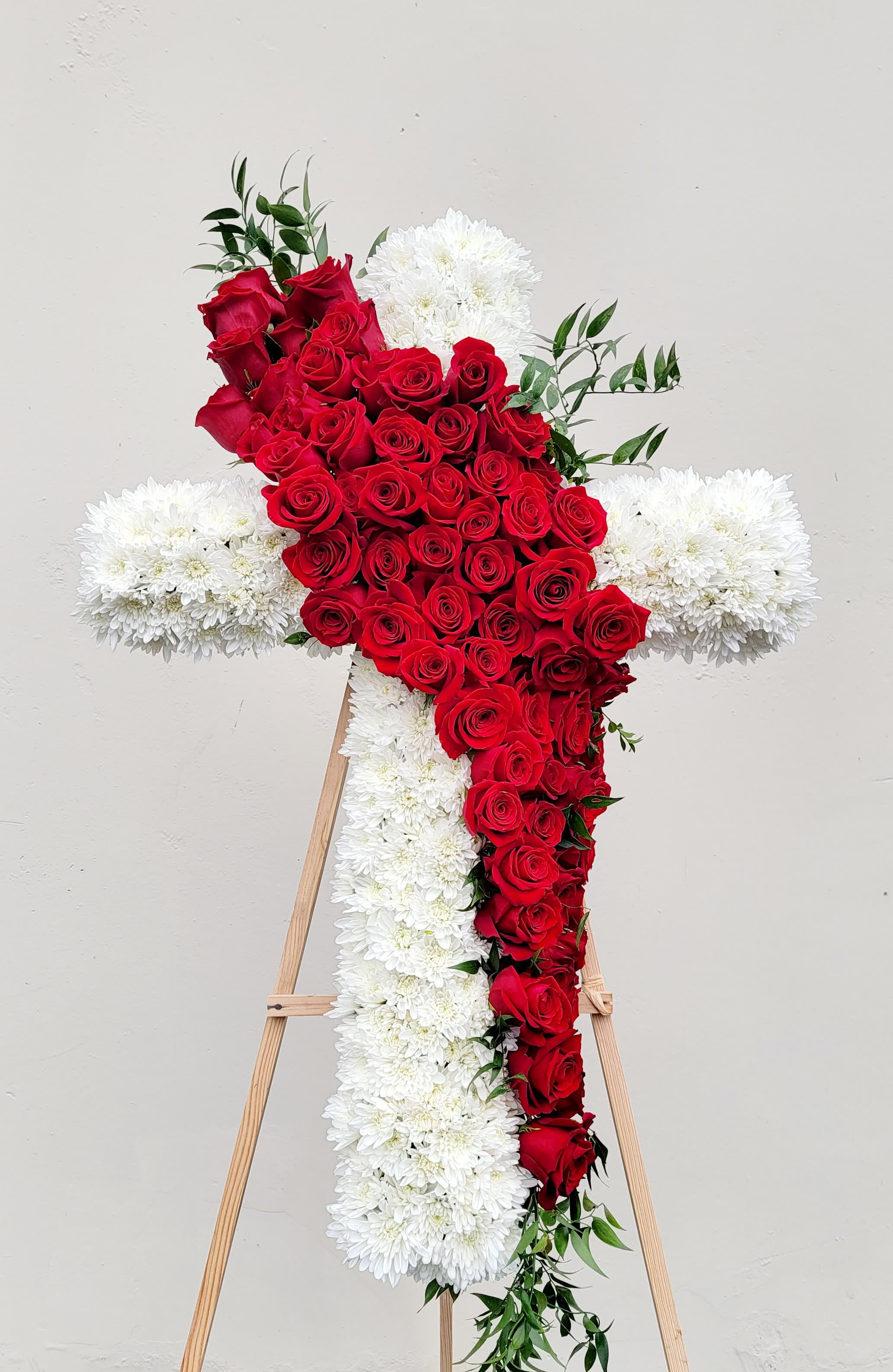 Red rose cross with white flowers on a wooden easel