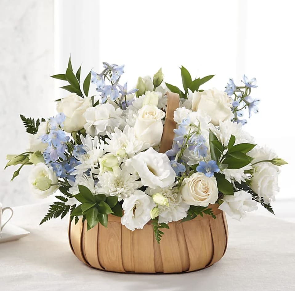 White and pale blue flower arrangement in a wooden basket