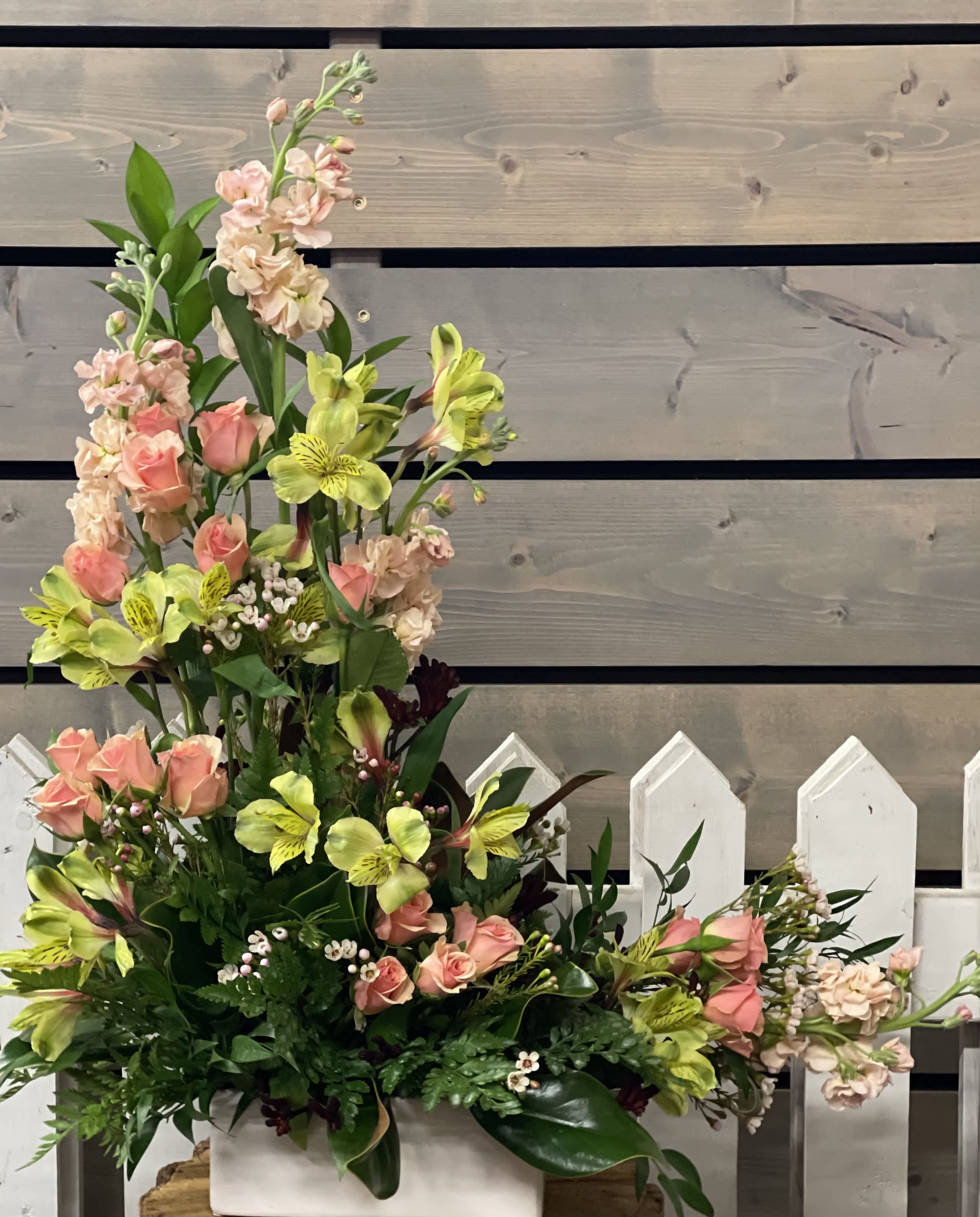 Tall floral arrangement with pink roses and yellow alstroemeria in a white container