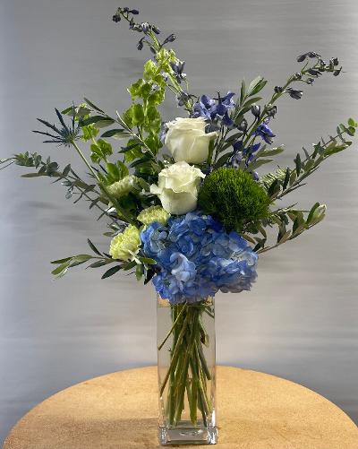 Blue hydrangeas and white roses in a clear glass vase