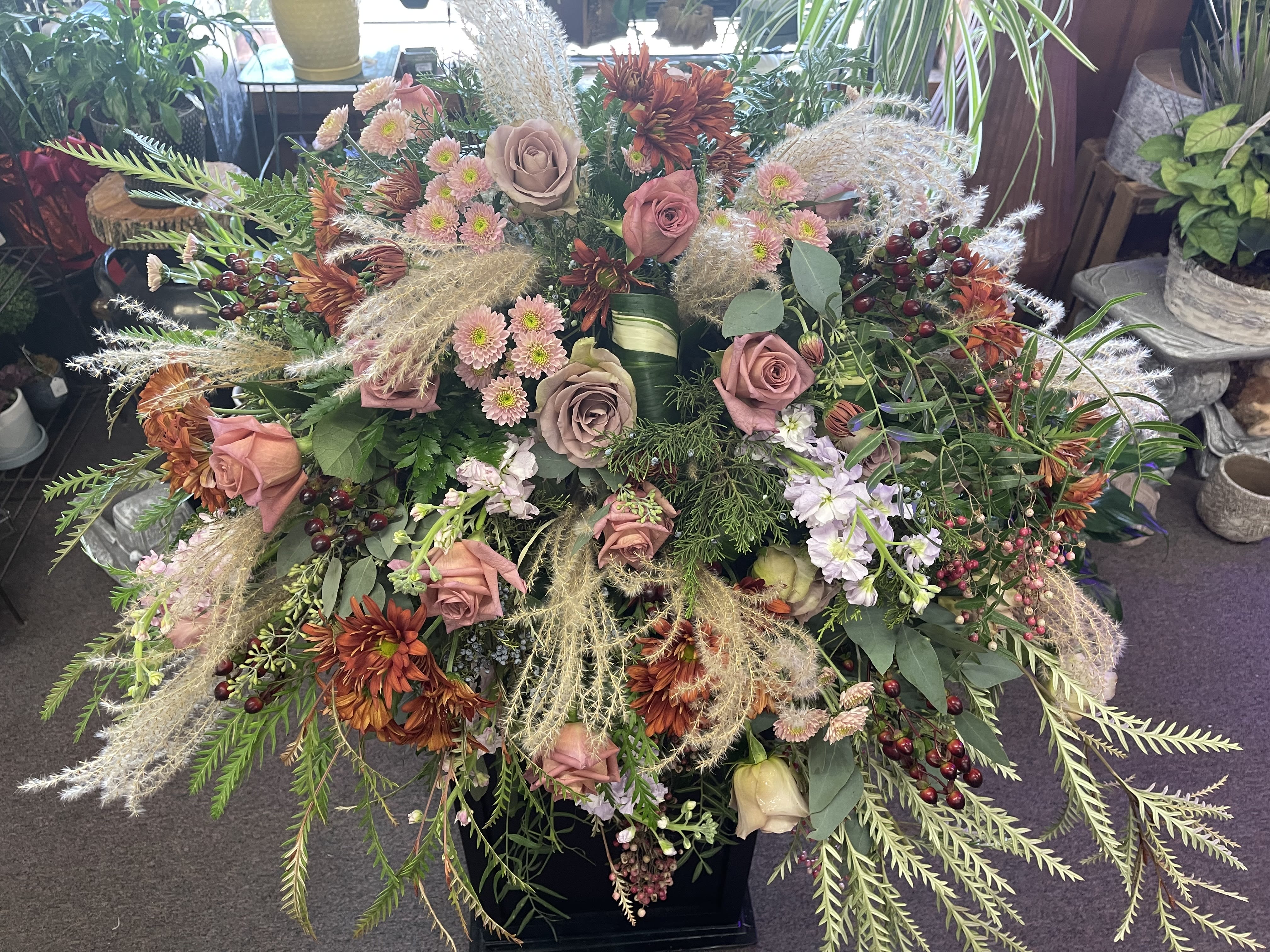 Large mixed floral arrangement with pink roses and orange mums in a black container