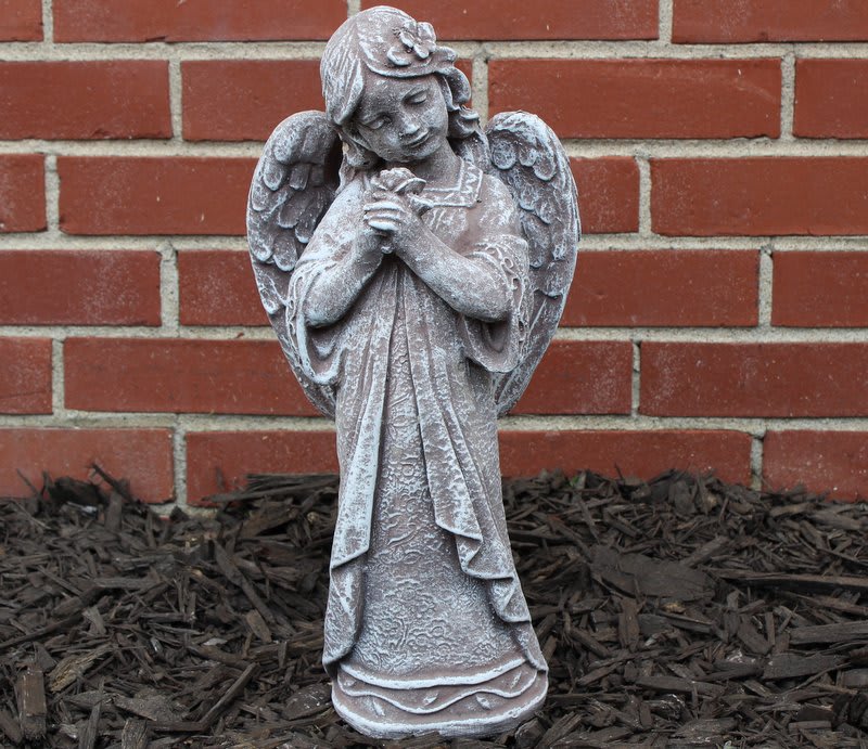 Stone angel statue standing against a brick wall
