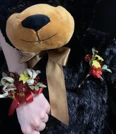 Teddy bear holding small floral accents and a ribbon