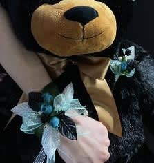 Plush teddy bear with a blue floral ribbon accessory