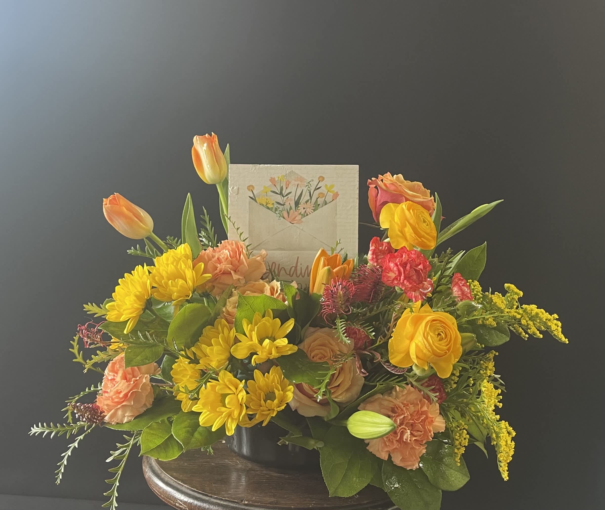 Mixed bouquet in a low container with yellow, orange, and pink flowers