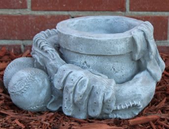 Stone garden sculpture of a baseball glove, ball, and cap