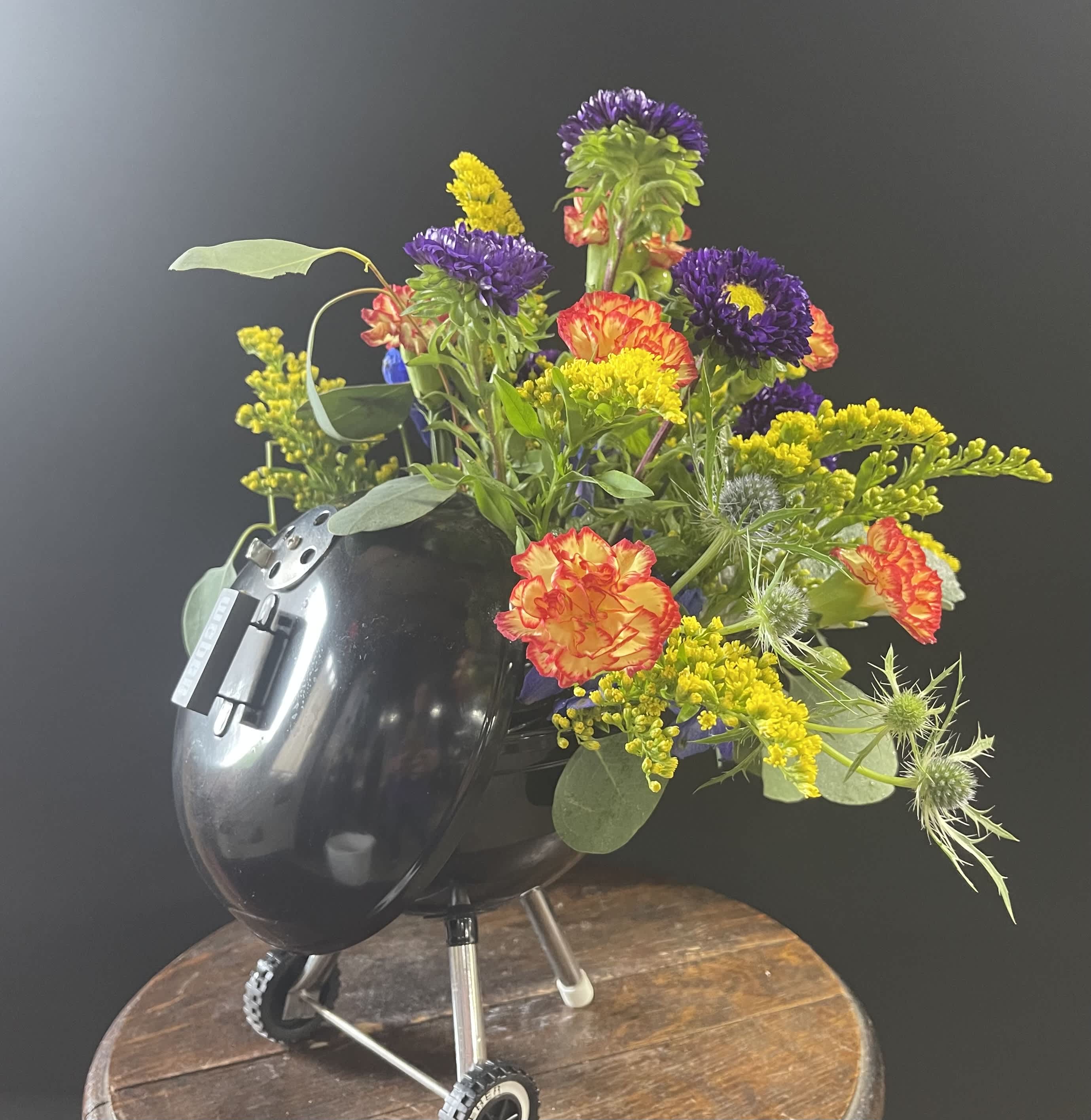 Colorful flower arrangement in a black helmet-shaped container