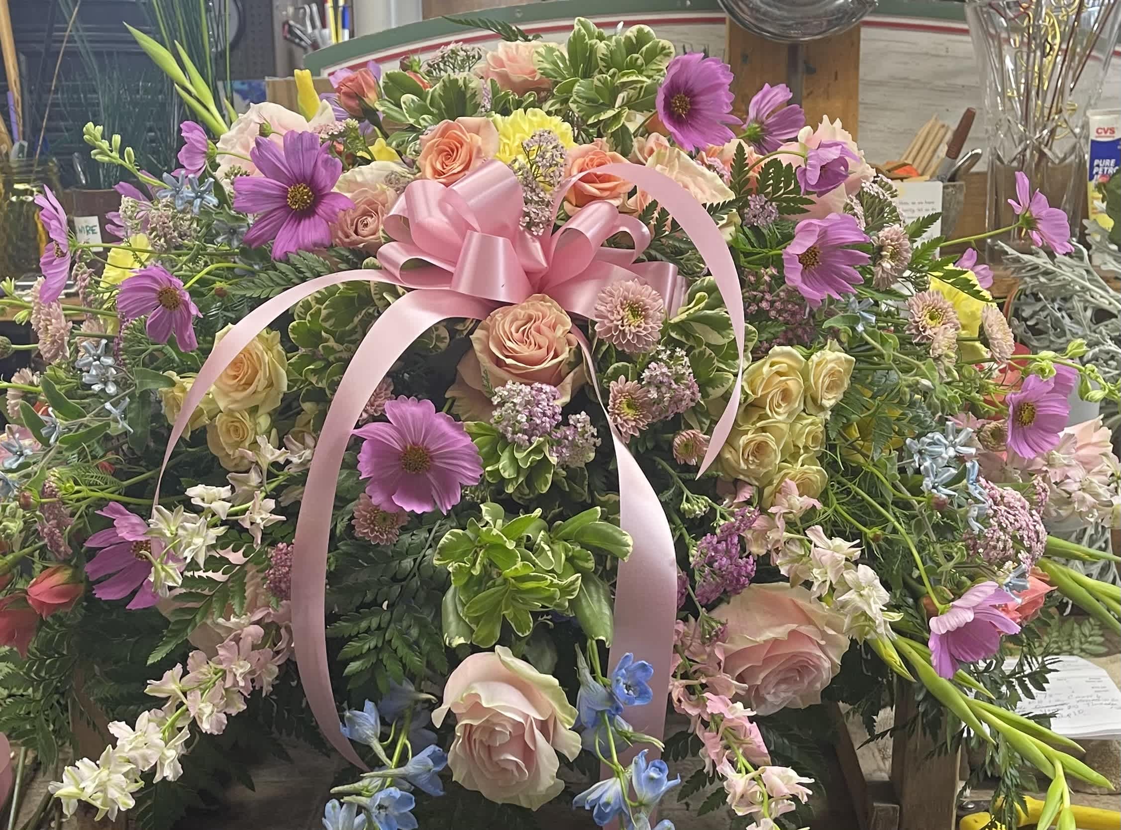 Large pink and purple floral arrangement with a pink ribbon bow