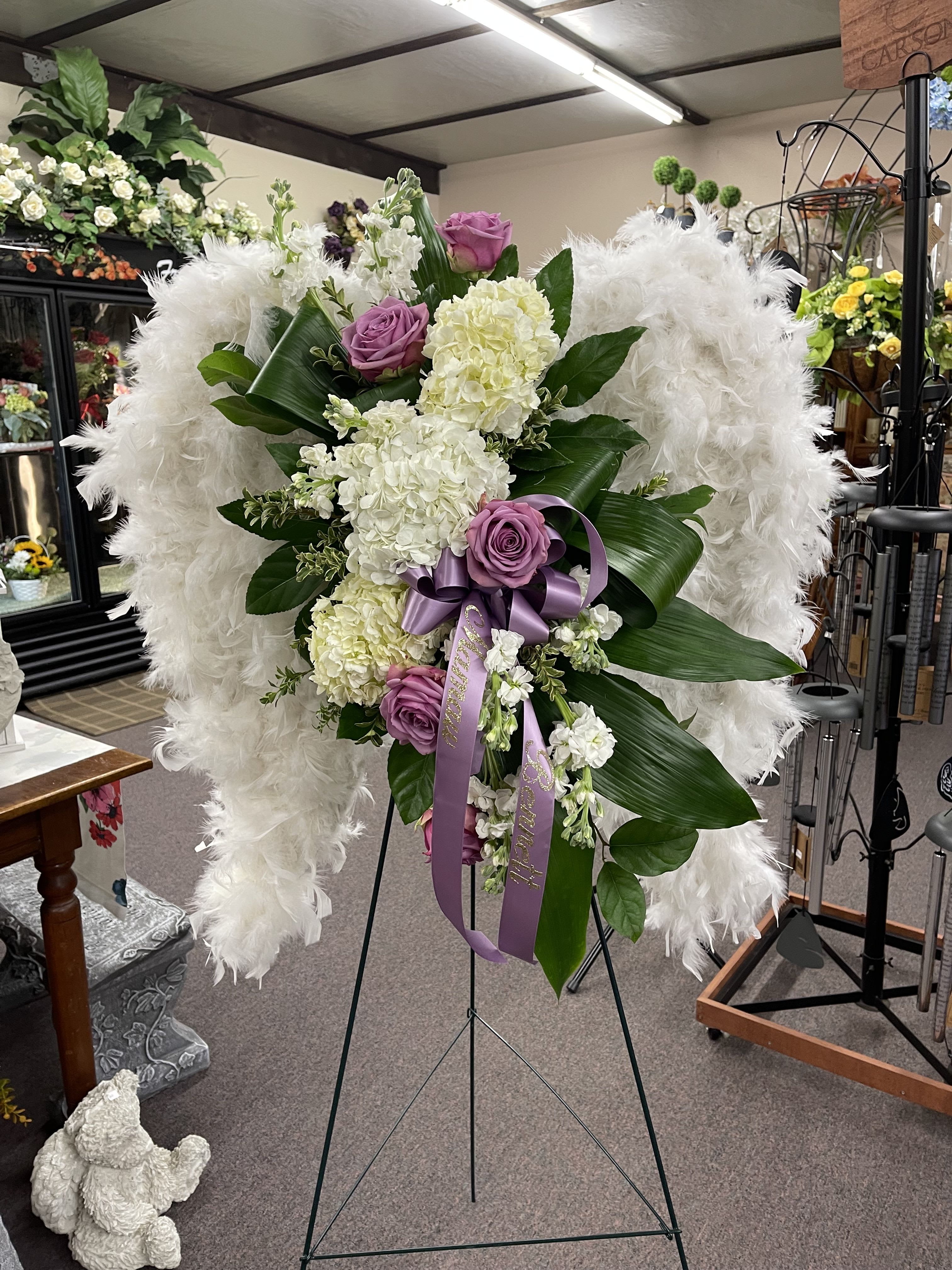 White and lavender floral standing spray with purple ribbon on an easel