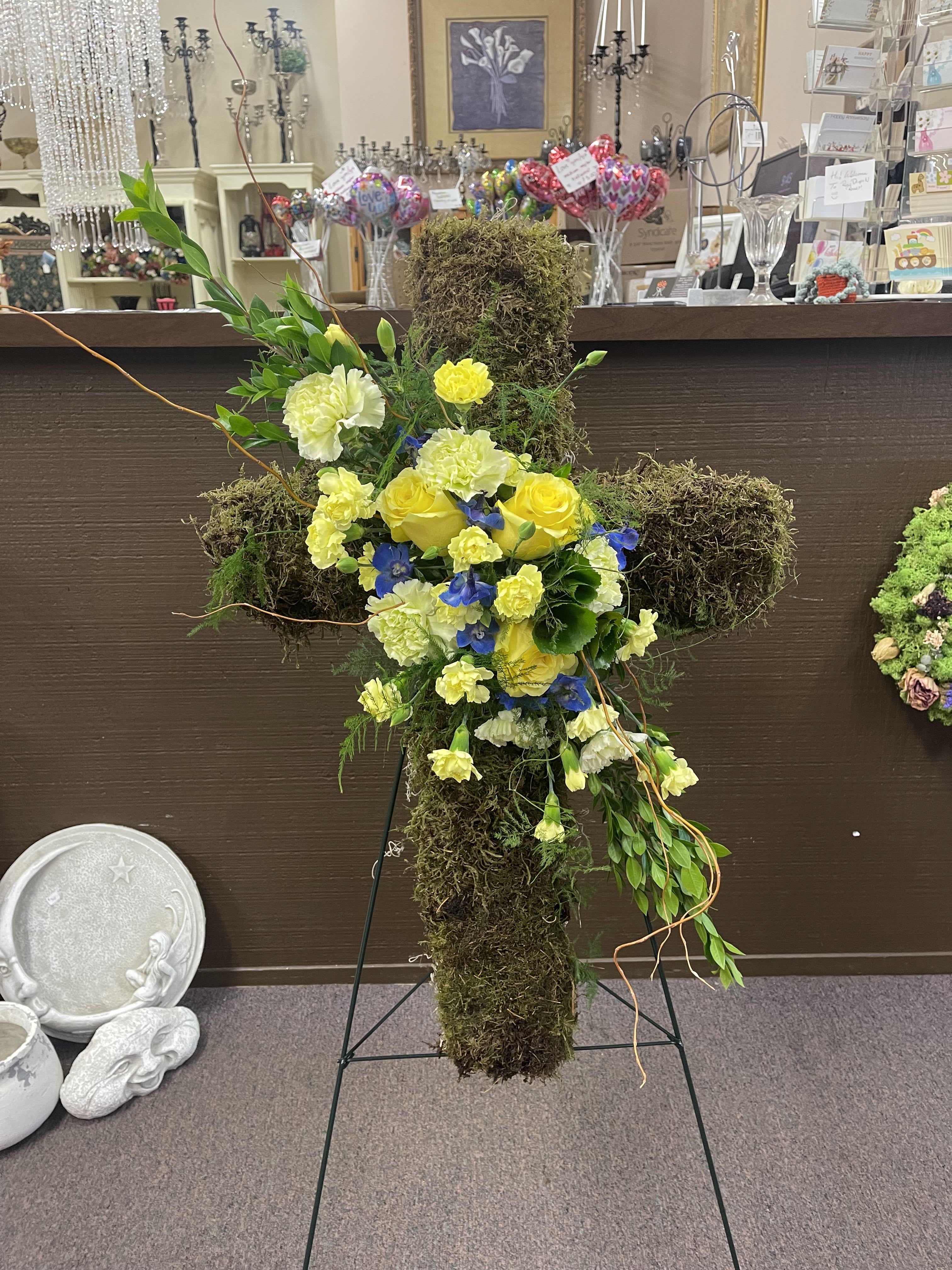 Moss-covered cross arrangement with yellow and white flowers