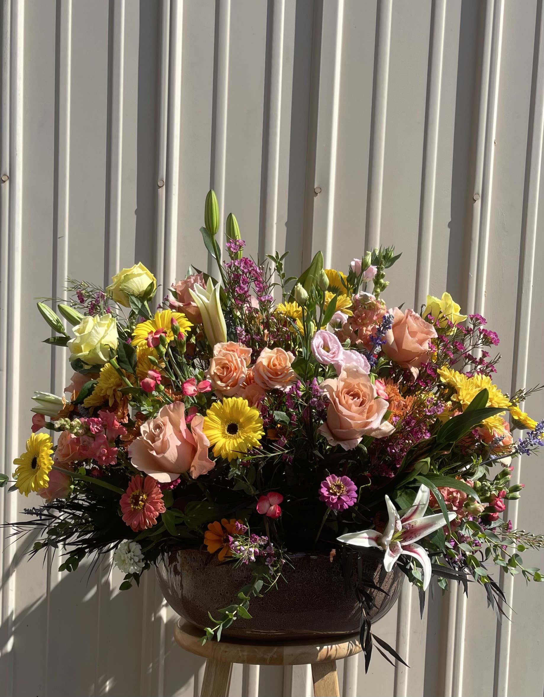 Large mixed bouquet in a dark bowl vase with pink, yellow, and white blooms
