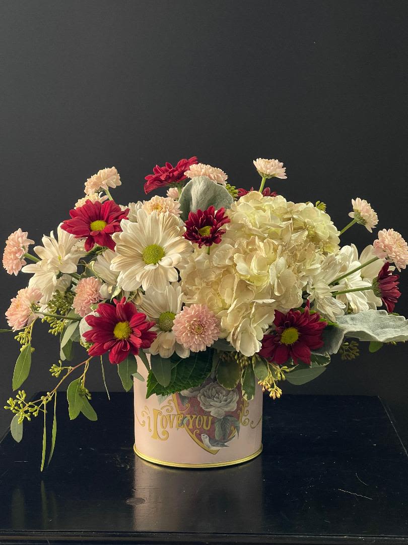 Mixed bouquet of white and red flowers in a decorative tin container