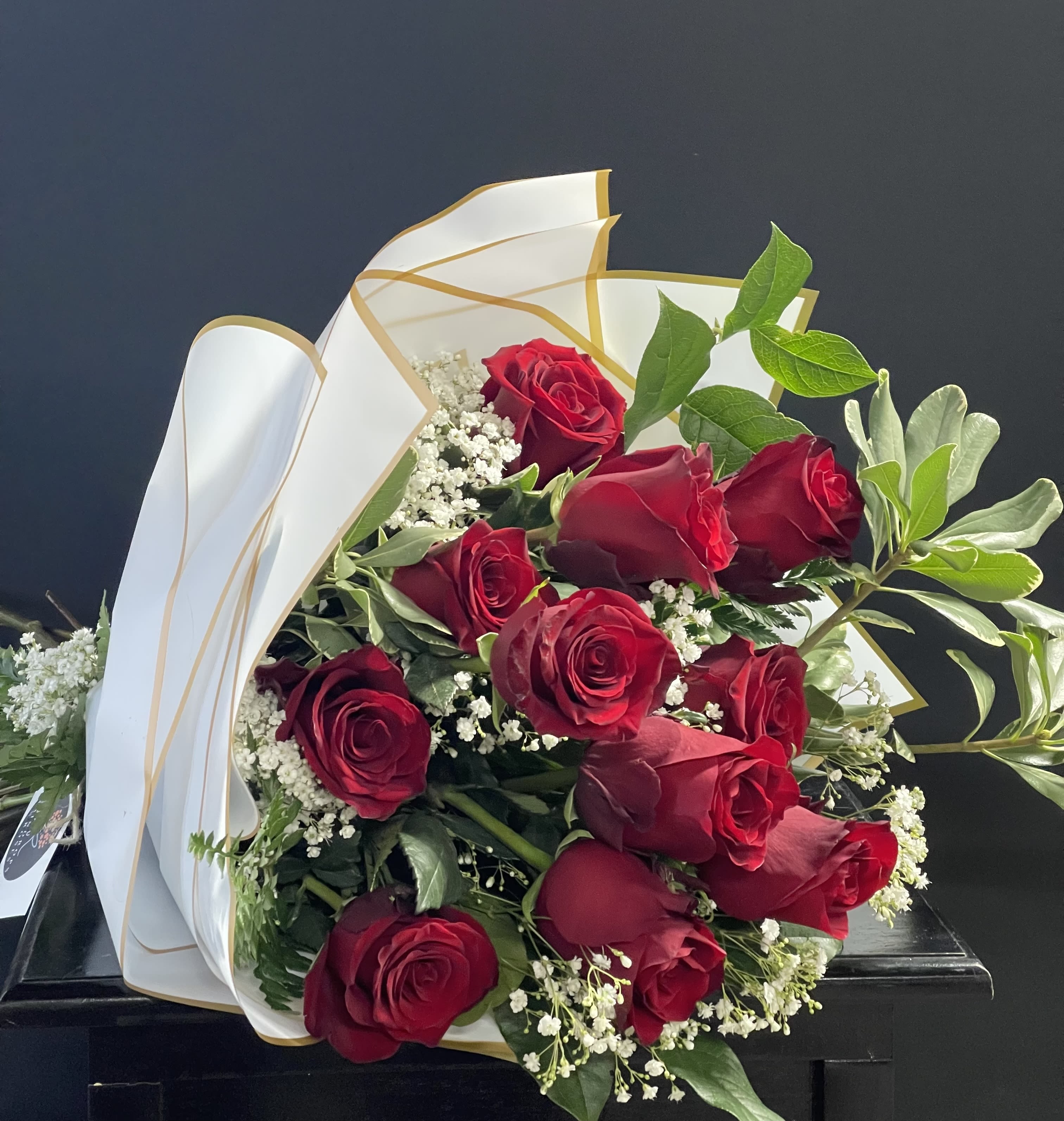 Bouquet of red roses with white filler flowers and white-gold wrapping