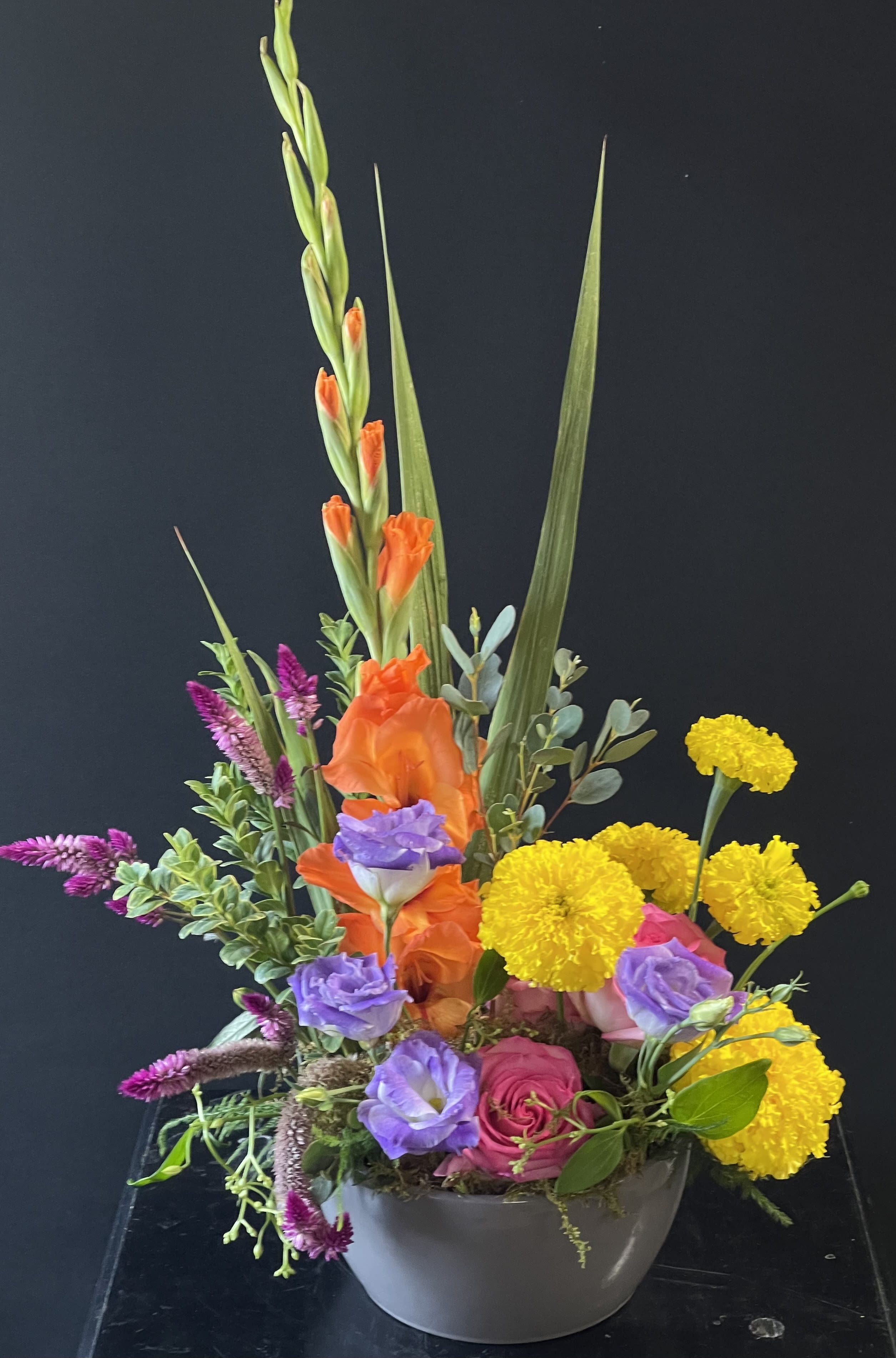 Colorful mixed flower arrangement in a gray bowl vase