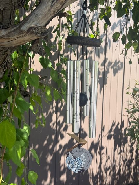 Silver wind chime hanging among tree branches