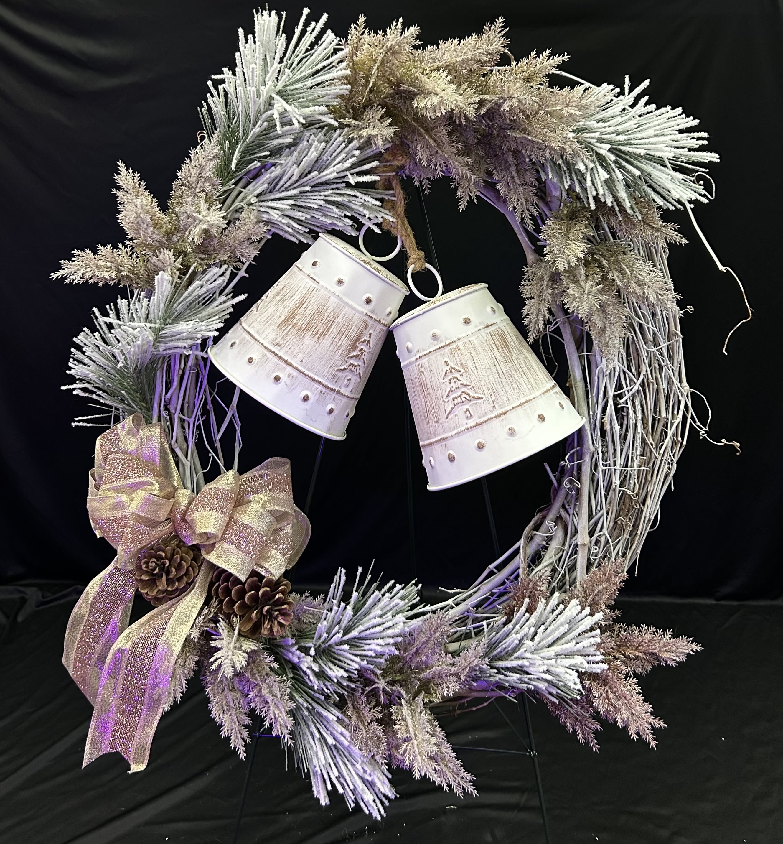 Decorative wreath with frosted branches, ribbon, pinecones, and hanging bells