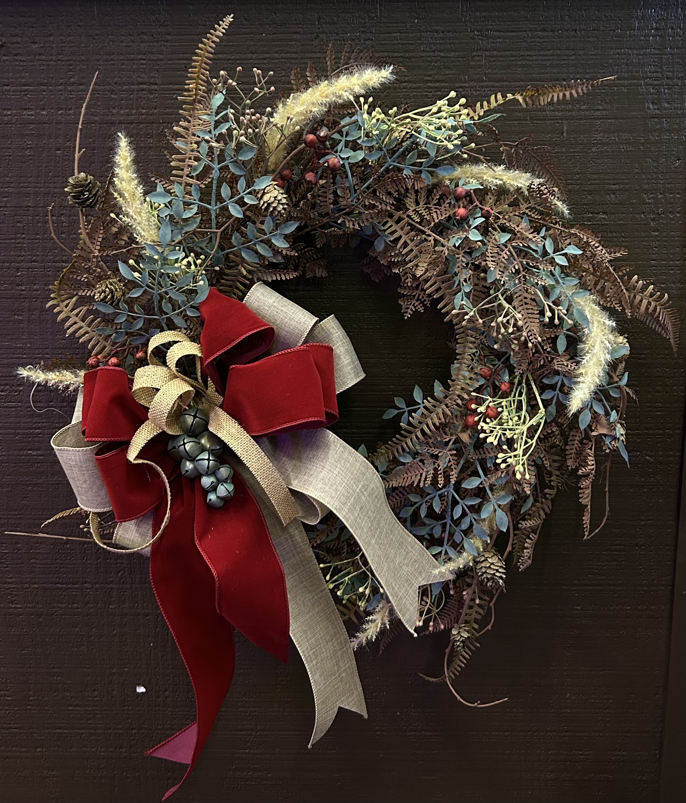 Rustic wreath with berries, pinecones, and a red ribbon bow