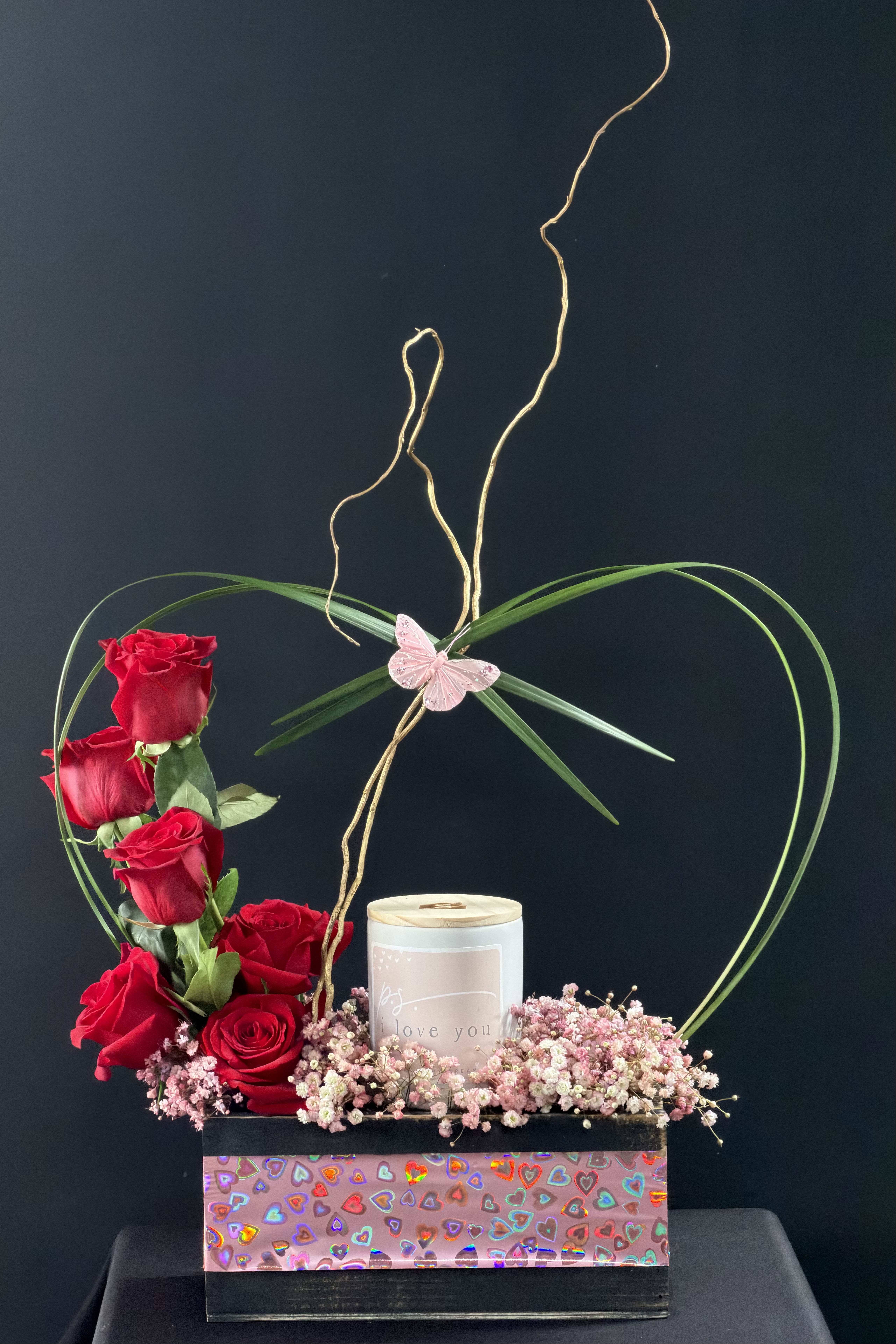 Red roses arranged with a candle in a heart-themed box