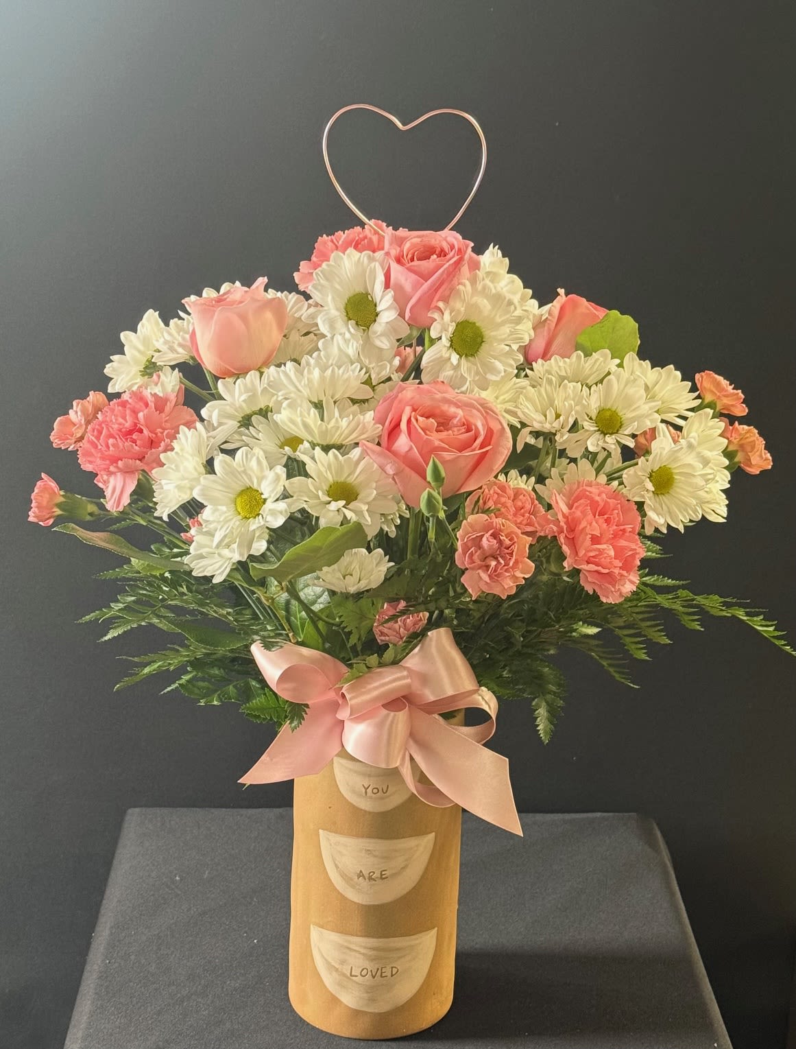 Pink roses and white daisies in a gold vase with a heart topper