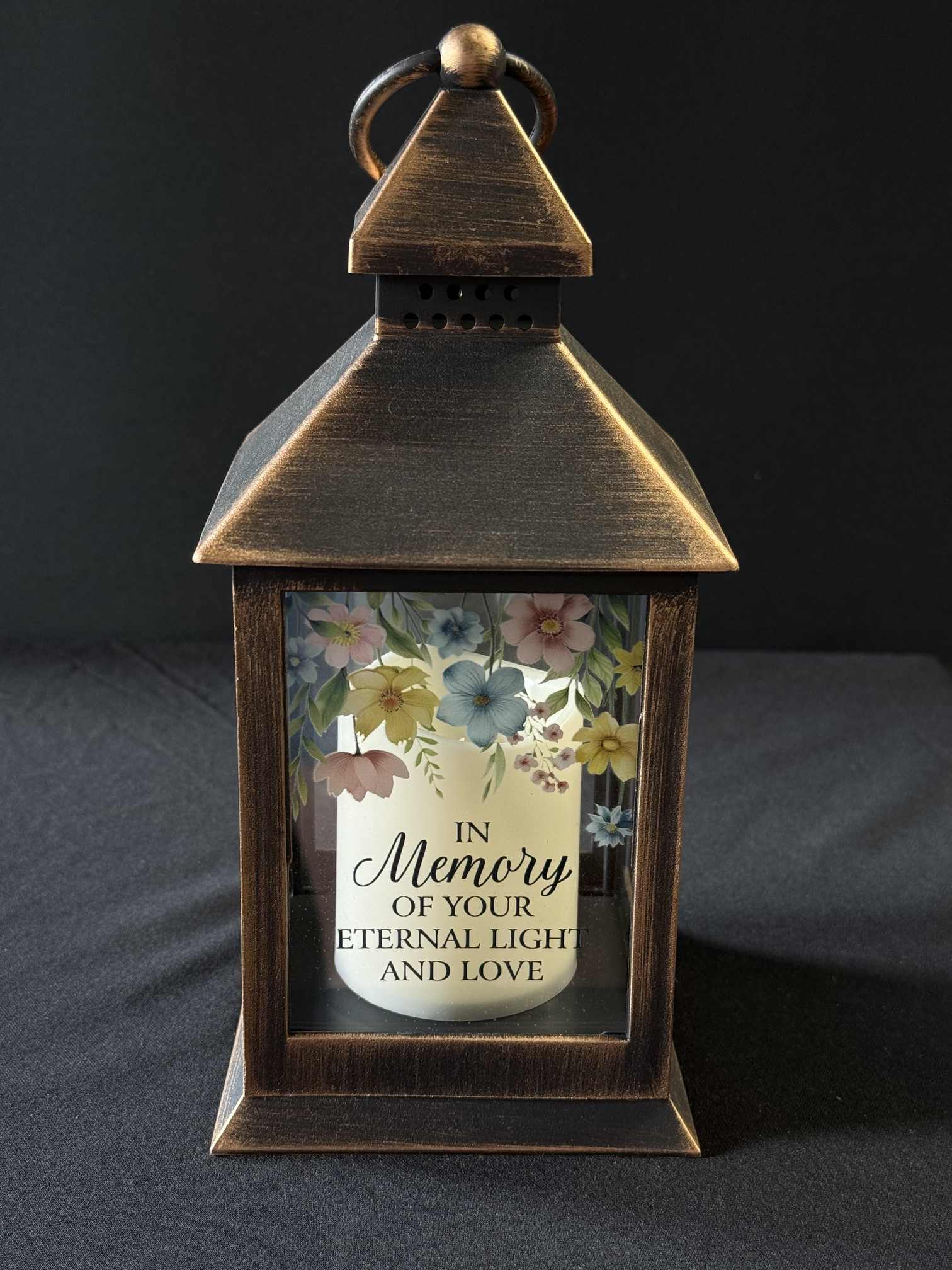 Bronze lantern with a memorial candle and pastel floral print
