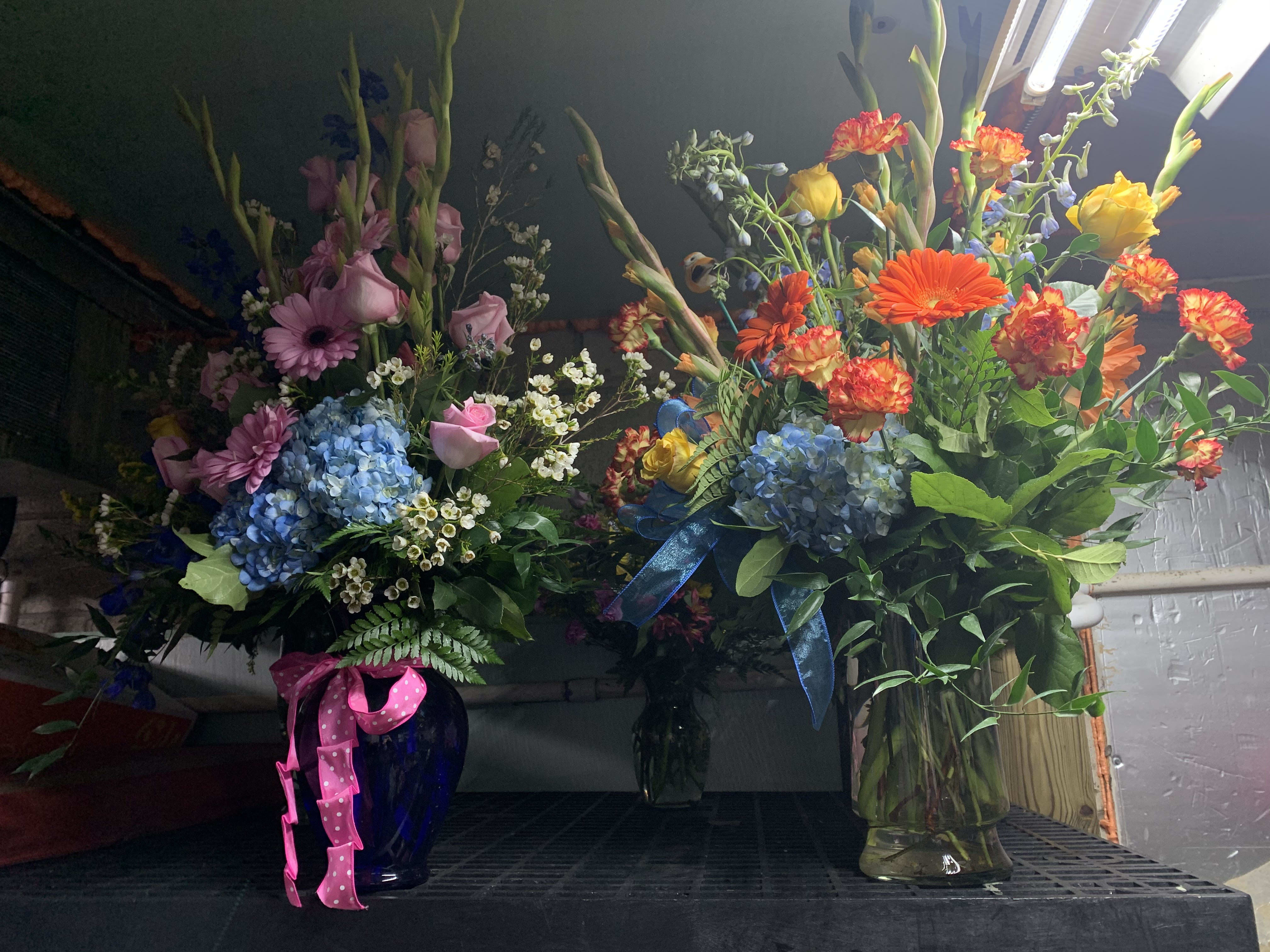 Two tall mixed flower arrangements in glass vases with ribbons