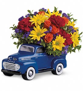 Blue truck figurine topped with a colorful flower arrangement