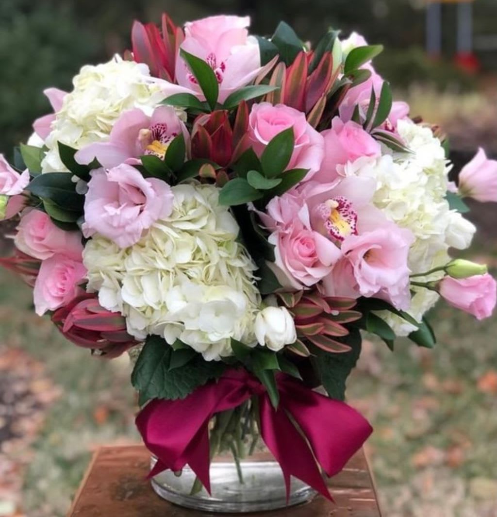 Pink and white bouquet in a glass vase with a magenta ribbon