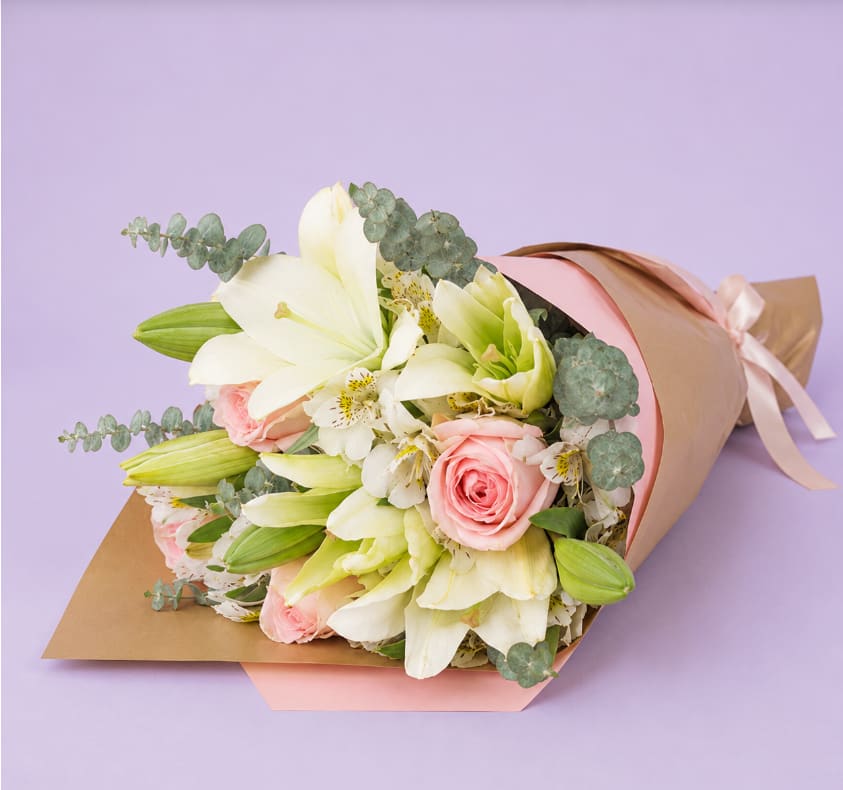 Bouquet of white lilies and pink roses wrapped in pastel paper