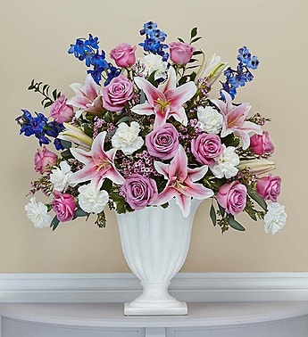 Pink roses and lilies arranged in a white vase