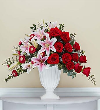 In Loving Memory - Our stunning and gracefully elegant asymmetrical arrangement of roses, Stargazer lilies, Matsumoto asters and more in shades of red and pink will provide a reflection of your sympathy and hope. Clusters of vibrant fresh blooms are displayed in a graceful keepsake pedestal vase. Elegantly crafted with satin finish and delicate fluting, a timeless vase that can be used to hold flowers or on its own as an objet d’art.  Our florists hand-design each arrangement, so colors and varieties may vary due to local availability Arrangement of roses, Stargazer lilies, Matsumoto asters, spiral and seeded eucalyptus, limonium, Italian ruscus and myrtle Arrives in our exclusive graceful ceramic pedestal vase; measures 10.375"H x 9.5"W Arrangement measures approximately 24"H x 27"L Appropriate to send to the funeral service or to the home