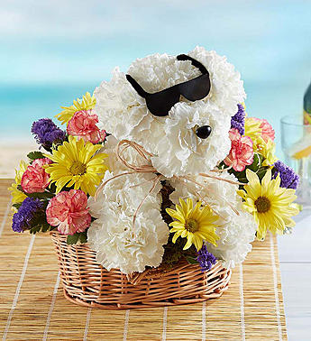 White teddy bear in sunglasses surrounded by colorful flowers in a wicker basket