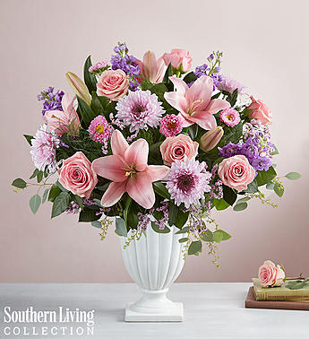 Pink and purple floral arrangement in a white pedestal vase