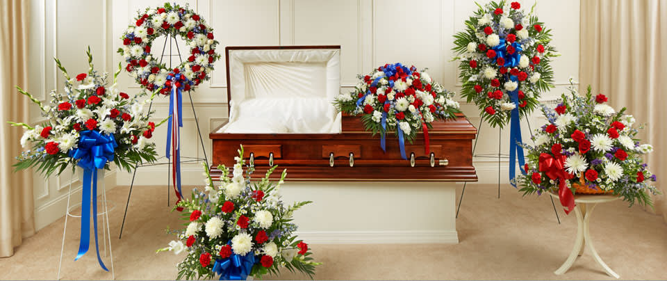 Casket surrounded by red, white, and blue funeral flower sprays