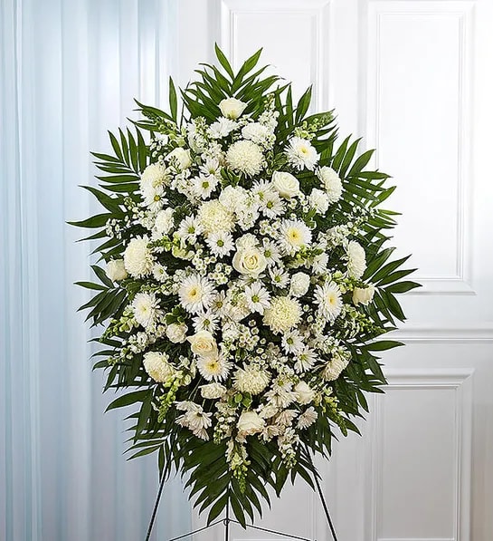 White funeral spray with daisies and roses on a standing easel