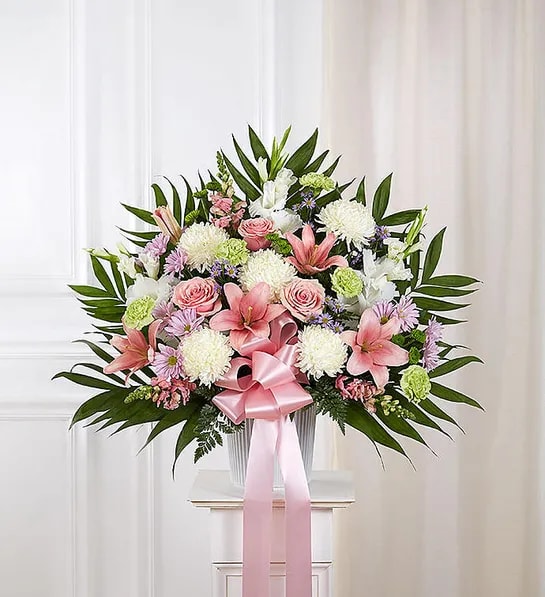 Pink and white floral arrangement with a pink ribbon in a vase
