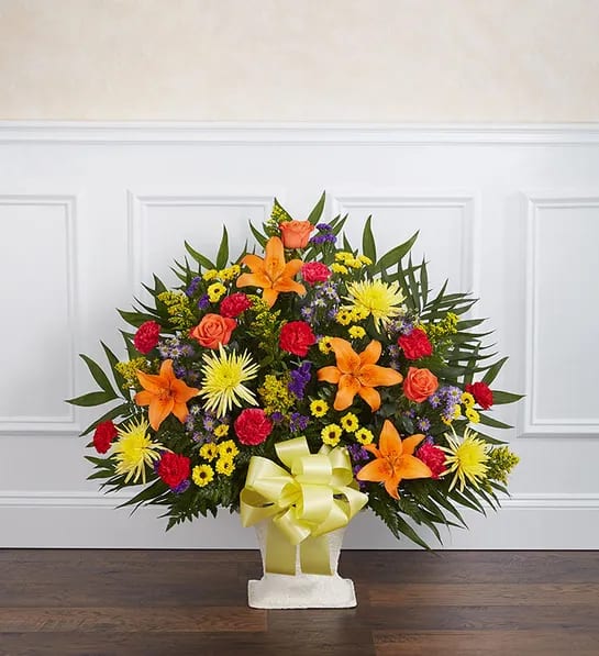 Colorful floral spray in a white basket with a yellow bow