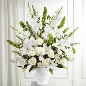 The Morning Stars Arrangement - The Morning Stars Arrangement is a brilliant expression of peace and soft serenity. White roses, carnations, gladiolus, stock, and Oriental lilies are accented with the bright green stems of Bells of Ireland and a gorgeous assortment of lush greens, while seated in a white designer plastic urn.