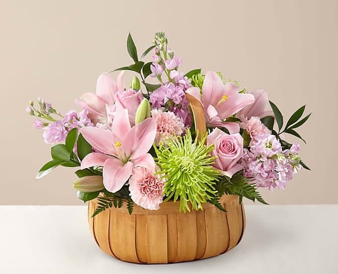 Pink lilies and roses arranged in a wooden basket