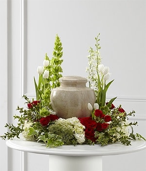 Red and white floral arrangement around a beige urn