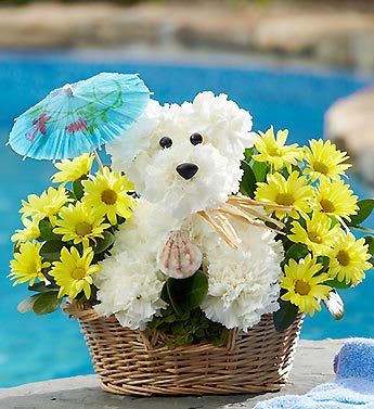 White teddy bear in a basket surrounded by yellow daisies and a blue paper umbrella