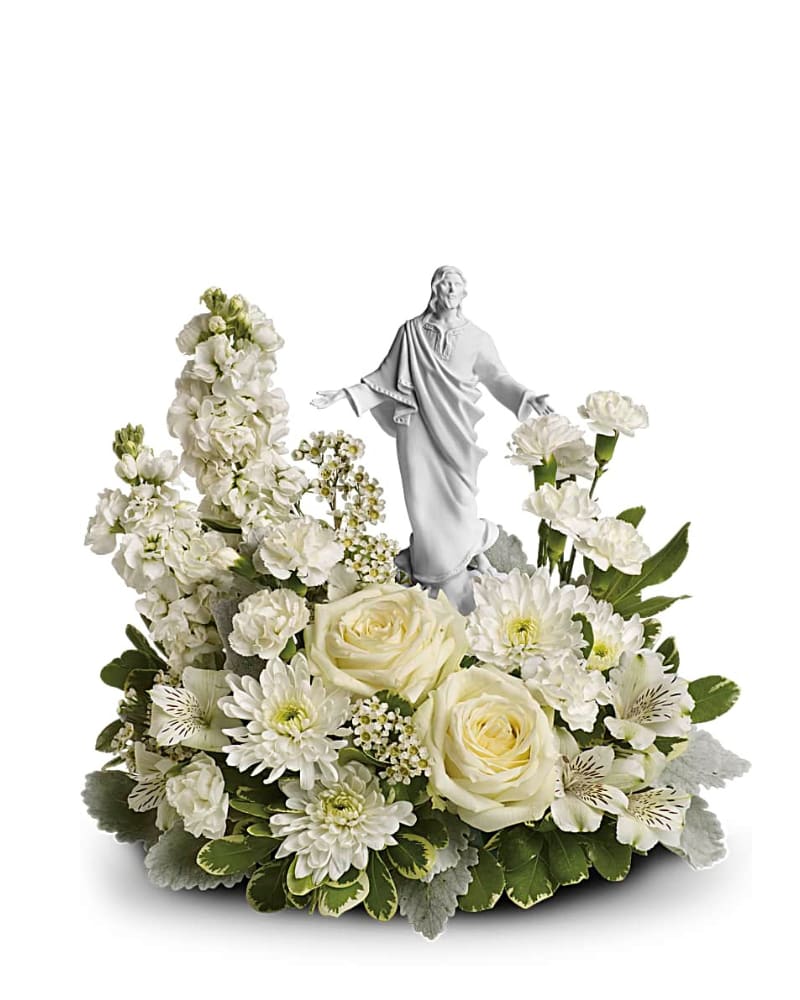 White floral arrangement with roses and mums surrounding a white Jesus figurine