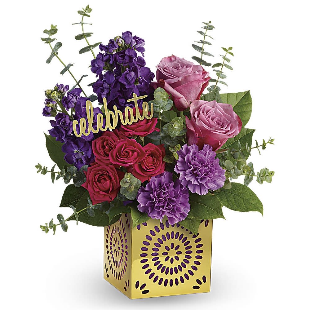 Bright arrangement of pink roses and purple flowers in a yellow cube vase with a celebrate sign.