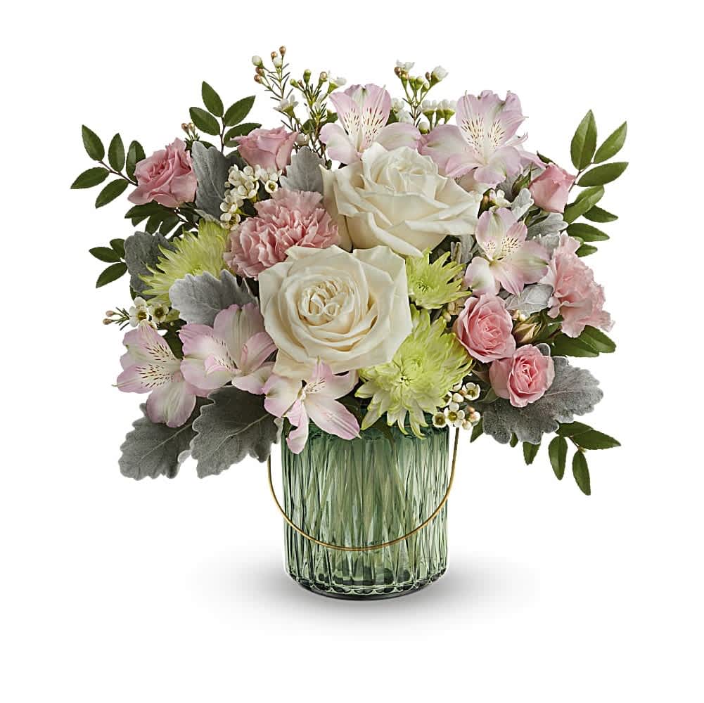Pastel arrangement of cream roses, pink blooms, and green mums in a green glass vase
